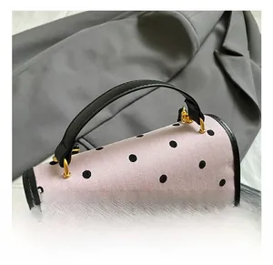 Detail of a purple polka dot backpack with a black leather handle and golden metal accents