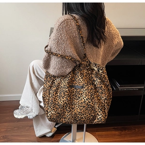 Detail of a large leopard print tote bag with long straps shown on a model
