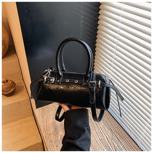 Close-up of black glossy patent leather bag with silver metal buckles and eyelets