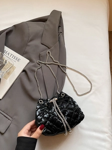 Close-up of quilted rhombus pattern bucket bag with silver chain and pearl detail