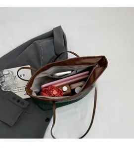 Internal storage detail of dark green woven tote bag with daily items and zipper pocket