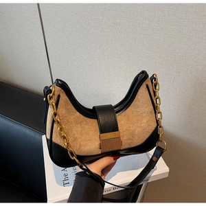 Close-up of hobo bag featuring color-block leather, gold chain, and textured metal buckle