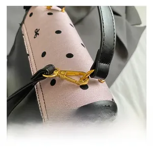 Close-up of pink polka dot handbag showing fine wavy texture and gold metal hooks