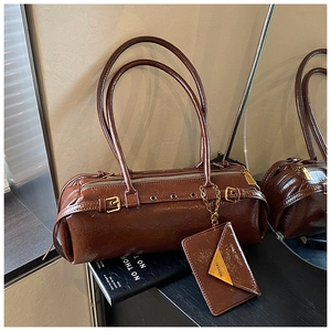 Detail of vintage brown patent leather boston bag with gold hardware and mini pouch charm