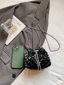 Close-up of a black quilted leather bucket bag with silver chain and glossy finish
