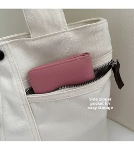 Close-up of a side hidden zipper pocket on a beige canvas tote bag with a pink wallet