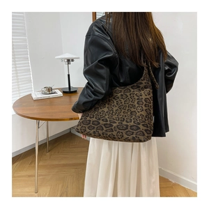 Modella che indossa una borsa tote scamosciata leopardata in un ambiente minimalista