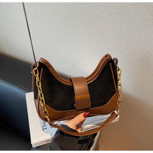 Close-up of retro brown leather and black suede patchwork bag with golden chain detail