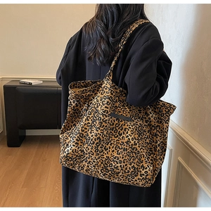 Close-up of leopard print canvas tote bag with long straps worn on shoulder