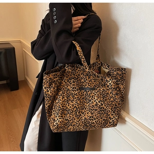 Detail of a large leopard print tote bag with an outer pocket on a female model