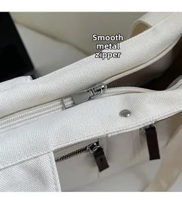 Detail of silver metal zipper on cream canvas tote bag showing smooth hardware quality