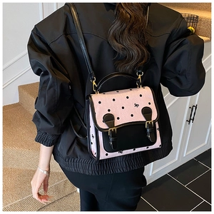 Detail of pink polka dot backpack with black leather flap and gold metal buckles