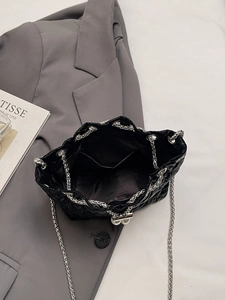 Top view of the black quilted bucket bag interior showing a pocket and silver chain strap