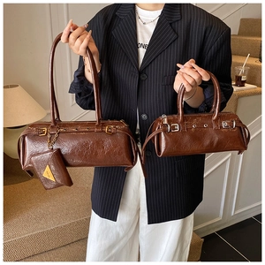 Detail of dark brown glossy cylinder bags with metallic buckles and small pendant charms