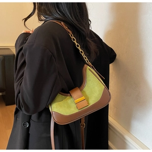 Detail of green suede hobo bag with dark brown leather trim and golden chain strap