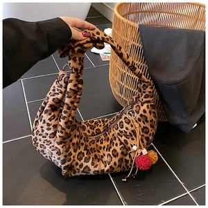 Detailed shot of leopard print hobo bag with knot handle and faux fur pompom charm