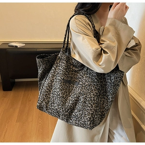 Close-up of leopard print tote bag with black leather label and long shoulder straps