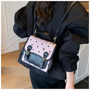 Pink polka dot backpack detail showing metal buckles, bow embroidery and black leather flap