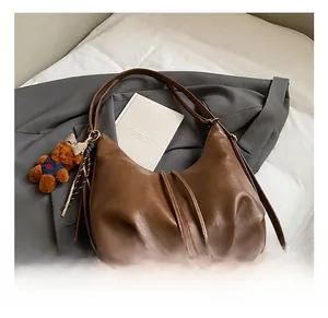 Detail view of dark brown dumpling bag with pleated drawstring and cute bear charm