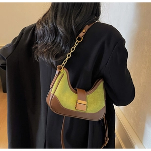 Sac demi-lune rétro vert avocat avec chaîne dorée sur une veste noire