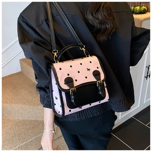 Detail of pink polka dot backpack with black bow accents and dual buckle straps