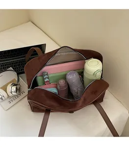 Spacious interior of dark brown suede tote bag showing laptop, bottle and daily items