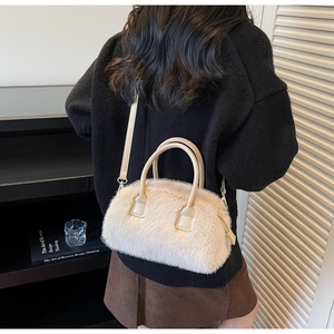Close-up of beige fuzzy faux fur Boston bag with leather handles in a chic interior setting