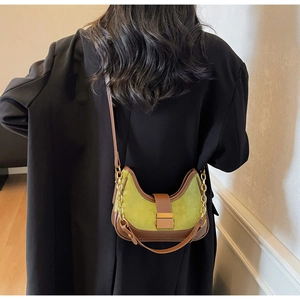 Détail du sac bandoulière en daim vert avec bordure en cuir marron et chaîne dorée