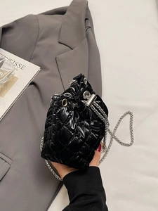 Detail of black quilted leather bucket bag featuring silver chain strap and drawstrings