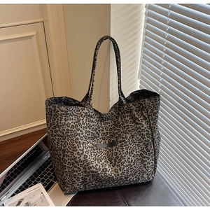 Macro shot of large leopard print tote bag with long straps on leather surface