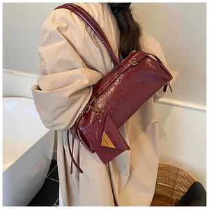 Detail view of burgundy leather pillow bag with metal accents and mini pouch