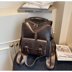 Close-up of vintage dark brown faux leather backpack with metallic buckles and wide straps