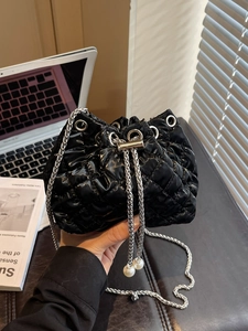 Close-up of black quilted bucket bag with silver chains and large pearl details