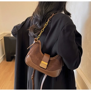 Detail showing brown half-moon shoulder bag with textured leather and gold buckle
