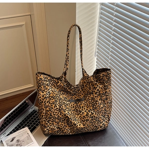 Detail of leopard print canvas tote bag featuring a stitched label and long shoulder straps