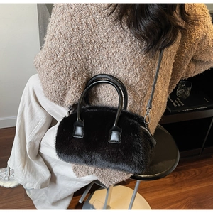 Detail of black faux fur handbag with leather handles and crossbody strap on shoulder