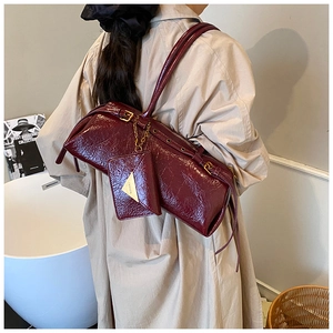 Detail of wine red patent leather shoulder bag with vintage texture and small pouch