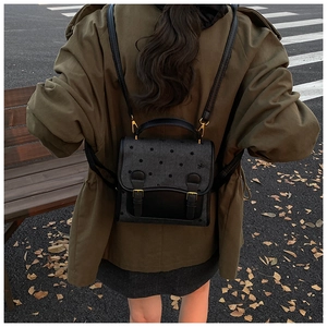 Detailed back view of a black polka dot backpack with leather straps for urban style