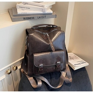 Close-up of vintage dark brown PU leather backpack with metallic buckles and texture