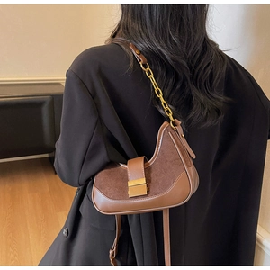 Detail of a brown suede half-moon underarm bag with gold chain and metal clasp