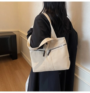 Close-up of beige canvas tote bag featuring double front zipper pockets and wide strap