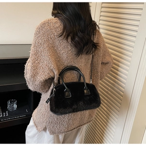 Detailed back view of a black faux fur handbag with leather straps in a home setting
