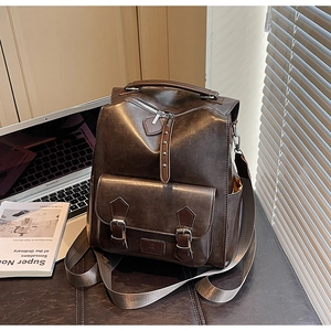 Close-up of vintage dark brown faux leather backpack with metallic buckles in lifestyle setting