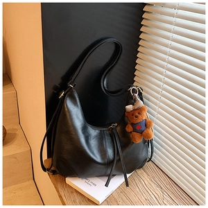 Detail of black hobo bag with textured faux leather, long zipper pulls and cute bear charm