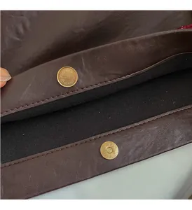 Close-up of magnetic metal closure and black suede lining on dark brown tote bag