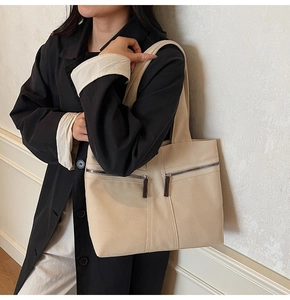 Detail view of beige canvas tote bag featuring double horizontal front zipper pockets