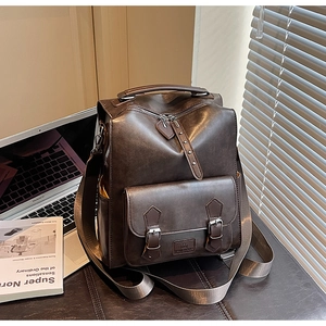 Detail view of dark brown vintage faux leather backpack with metallic zippers and buckle