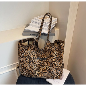 Close-up of leopard print tote bag with black woven label on a minimalist surface
