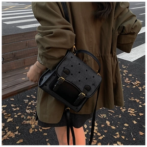 Outdoor street view of a retro black polka dot backpack with elegant gold hardware detail