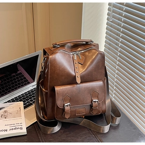 Detail of vintage dark brown leather backpack with silver hardware on a desk setup